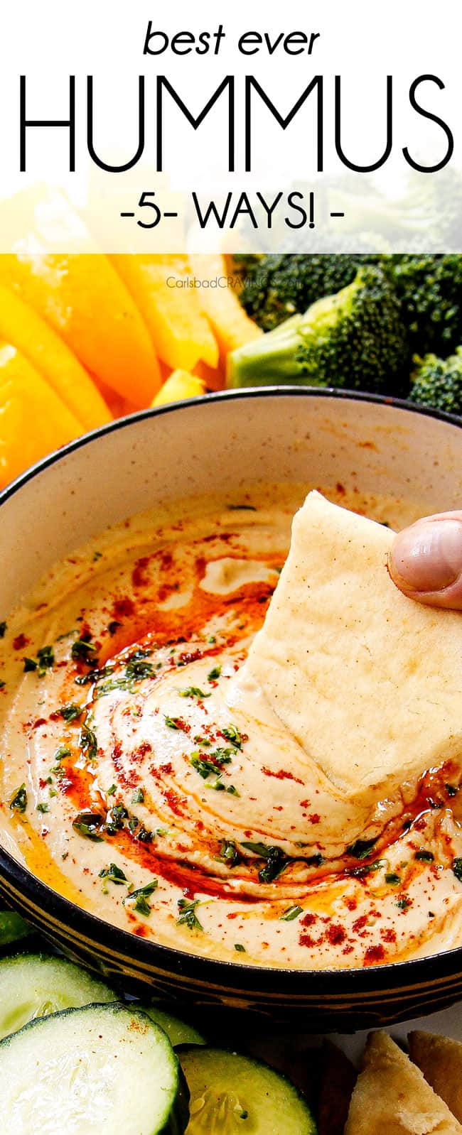 up close of dipping pita into hummus recipe in a black bowl