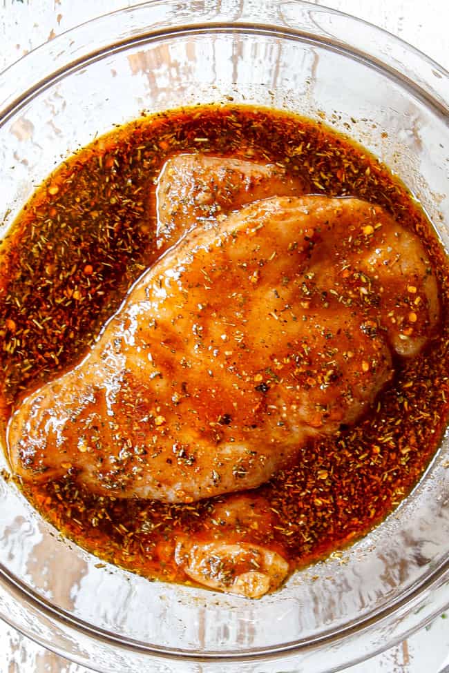showing how to make balsamic chicken marinade by adding balsamic vinegar, honey, olive oil, lemon juice and herbs to a glass bowl and adding chicken