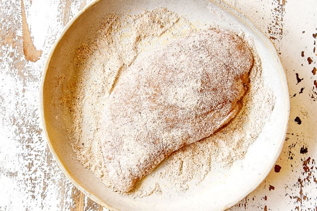 showing how to make Chicken Florentine recipe by dredging chicken in flour 
