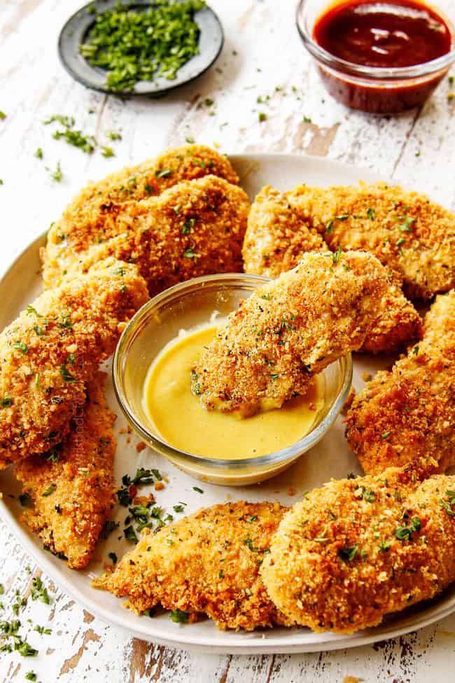 dipping Parmesan crusted chicken into honey mustard sauce
