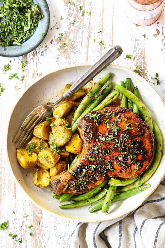 top view of brown sugar pork chops in a round tan dish with green beans and potatoes