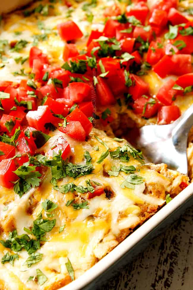 showing how to serve King Ranch Chicken Casserole by garnishing with tomatoes and cilantro