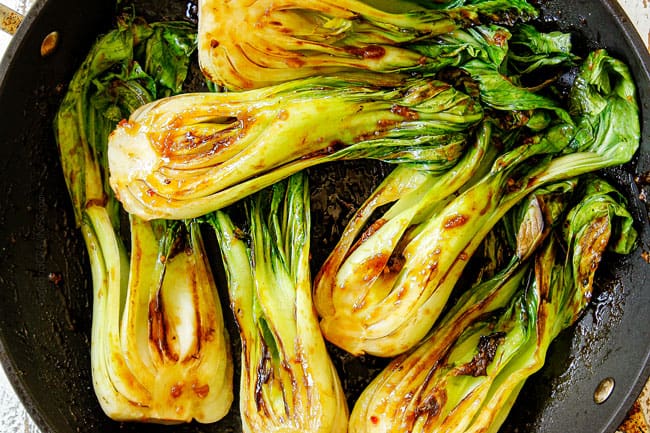 showing how to cook bok choy recipe by stirring bok choy with sauce