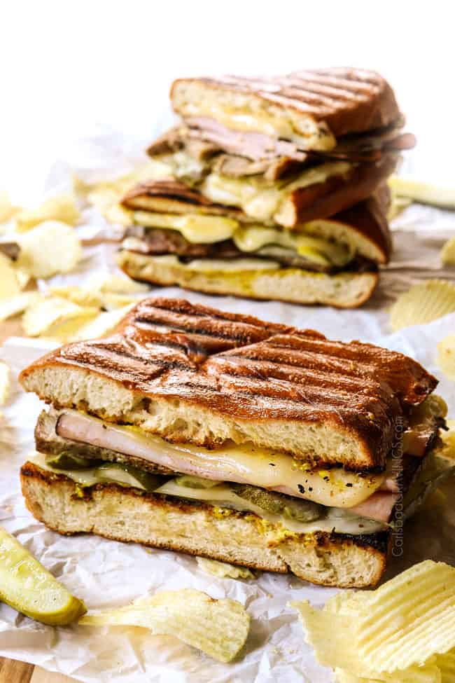 Cubano sandwich (Cubano) on a wood tray surrounded by potato chips showing how crispy  the bread is