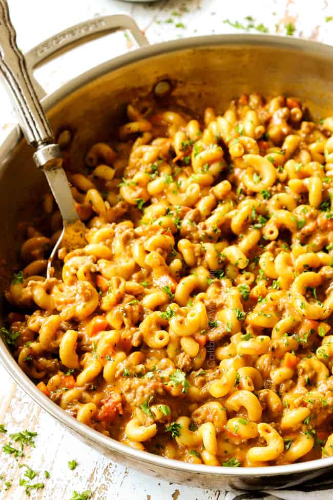 a spoon in a skillet of homemade hamburger helper recipe showing how creamy and cheesy it is