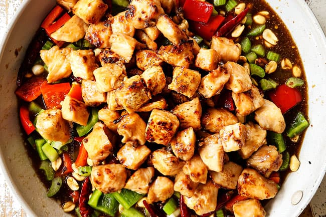 showing how to make kung pao chicken by adding chicken and sauce to the stir fried vegetables
