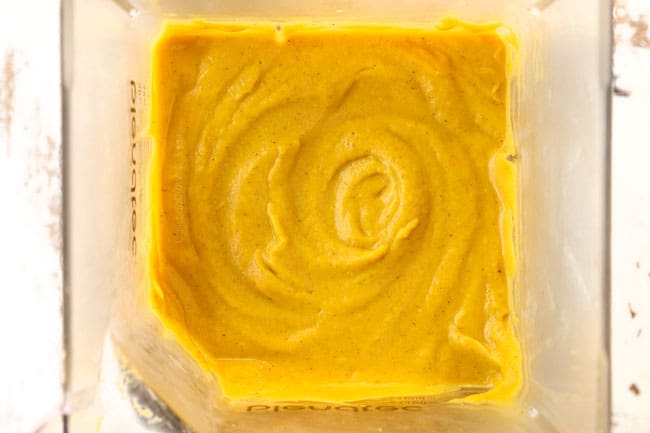 showing how to make pumpkin soup by blending the soup until smooth in a blender