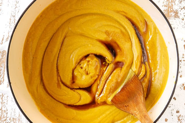 showing how to make pumpkin coconut soup by stirring in maple syrup and apple cider vinegar