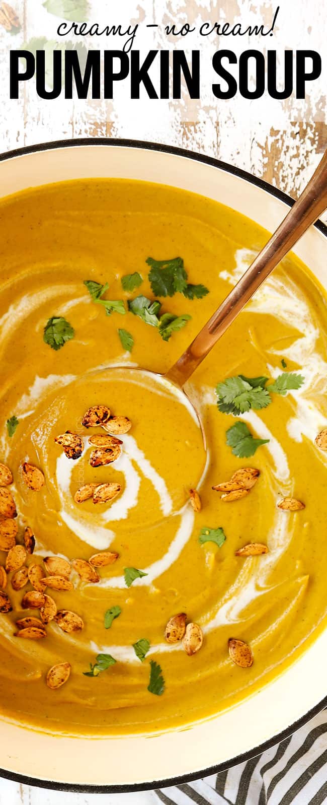 top view of pumpkin soup garnished with coconut milk in a white Dutch oven