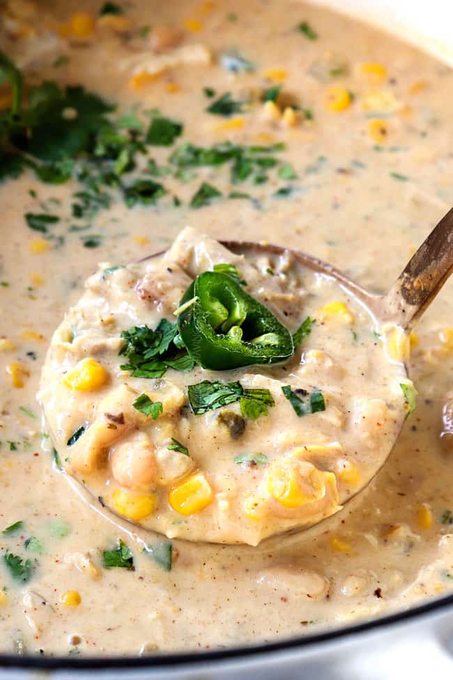 showing how creamy white chicken chili is by scooping up some of the soup