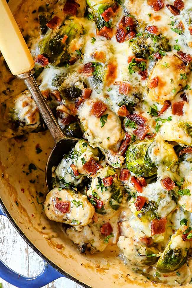 top up close view of a spoon of creamy Brussel sprouts with bacon in large pan showing how creamy they are