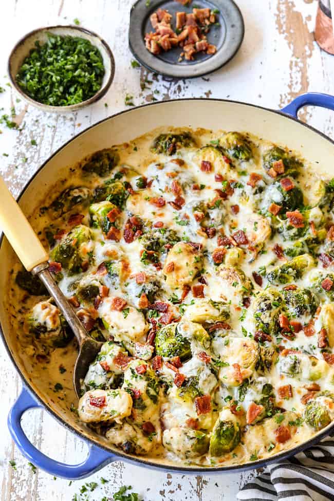 a serving spoon scooping up creamy Brussel sprouts in large pan
