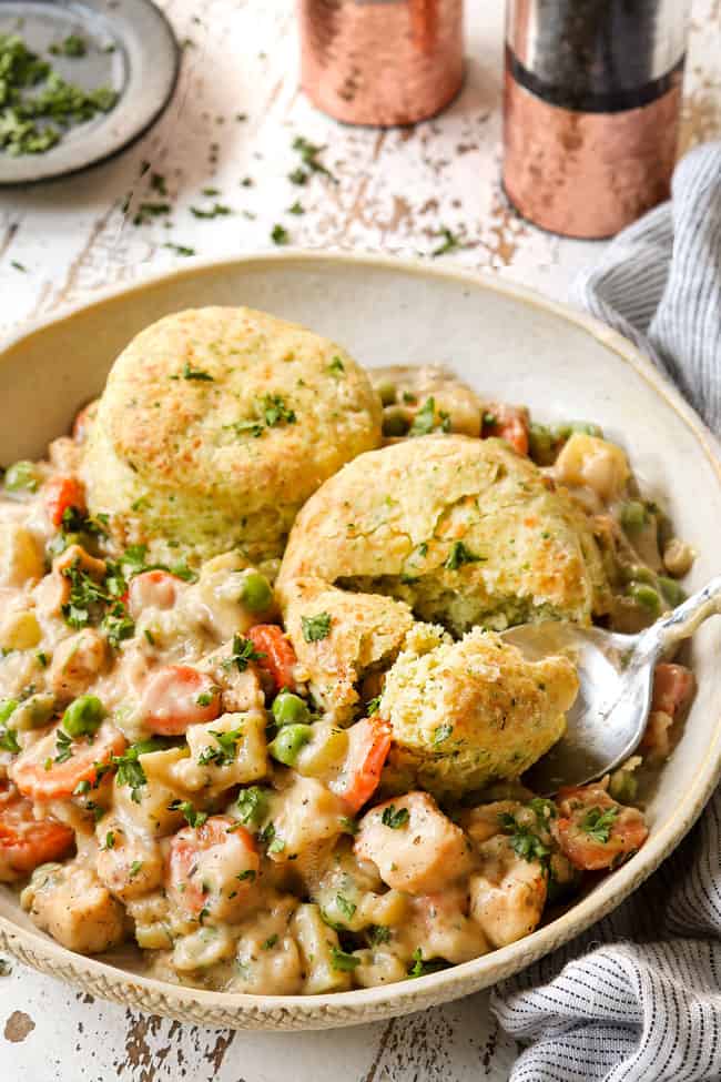 chicken pot pie with biscuits recipe with a spoon cutting one of the biscuits