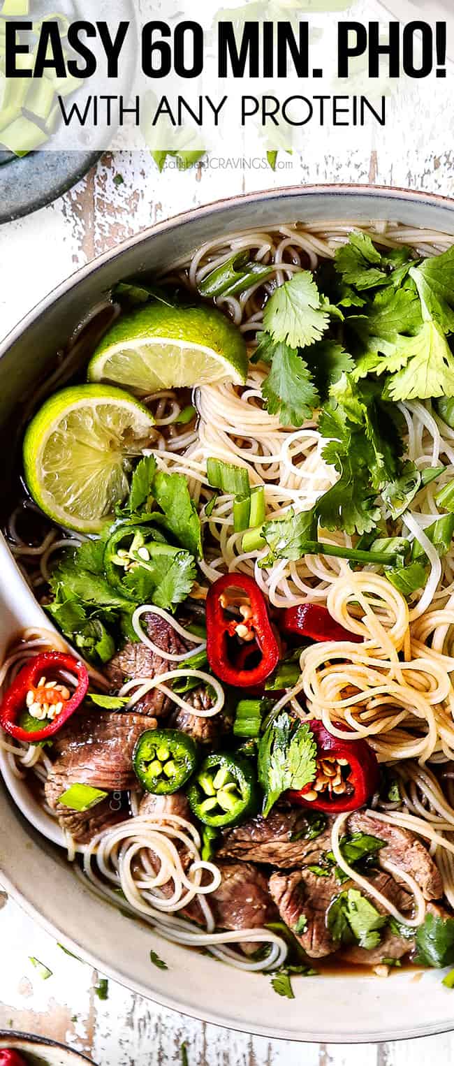 top view of a bowl of pho with rice noodles, beef, chilies, cilantro, basil, and limes