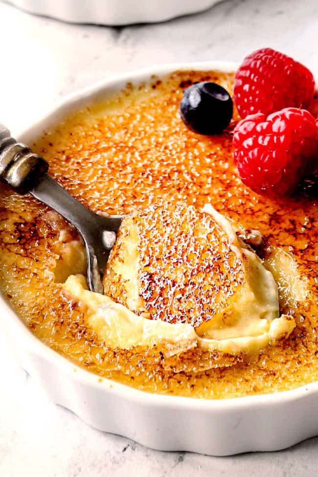 up close of a spoon digging into easy crème brûlée showing the creamy custard and the hard top 