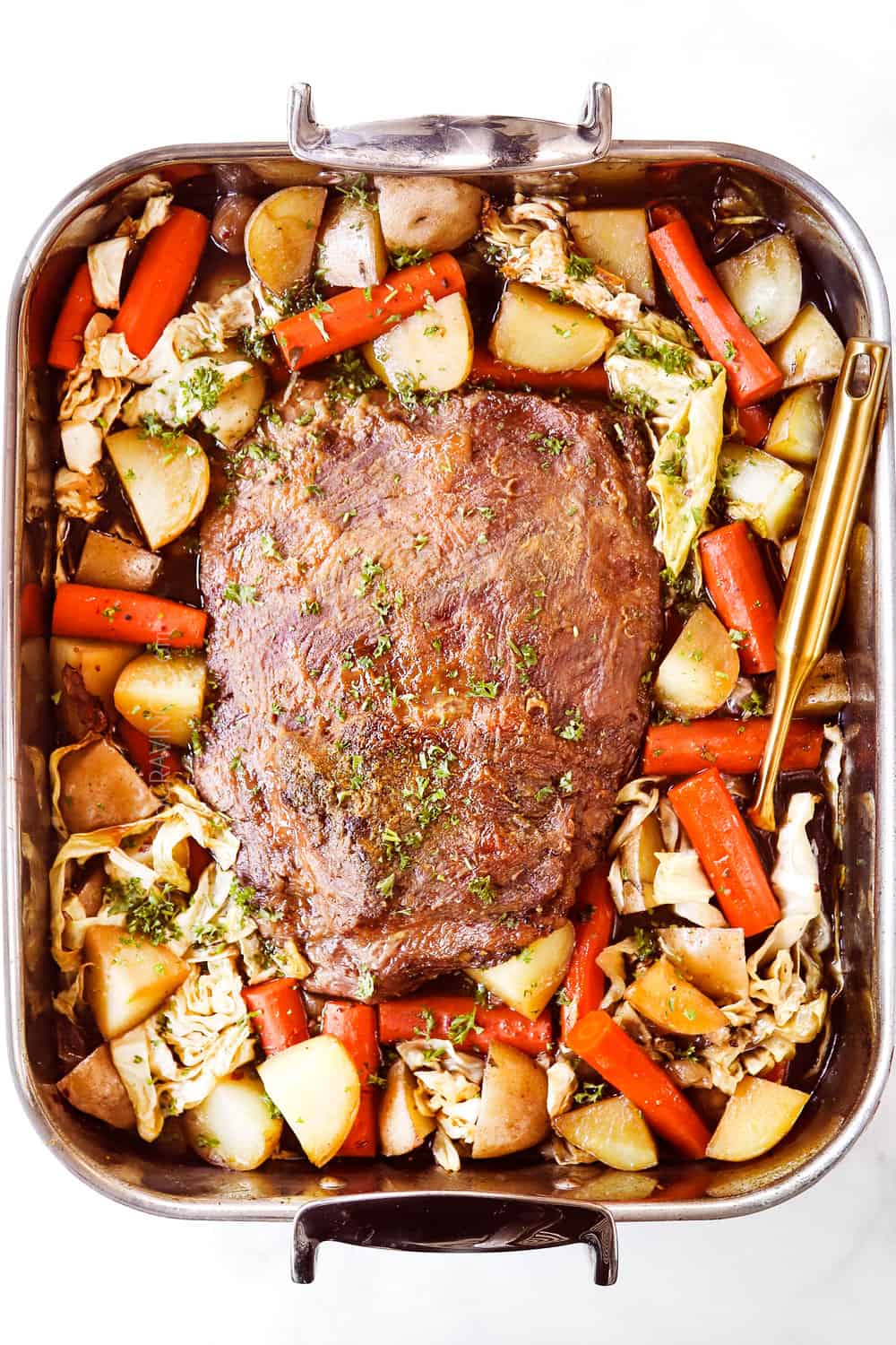 showing how to cook corned beef by roasting in a pan in the oven with cabbage, carrots and onions