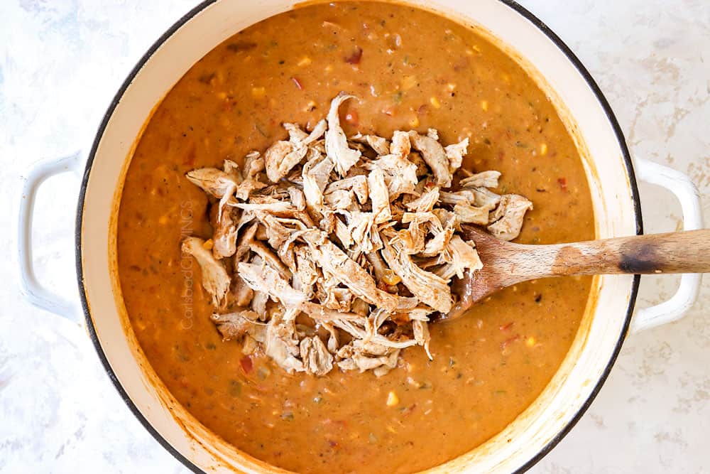 showing how to make buffalo chicken chili by adding shredded chicken back to soup