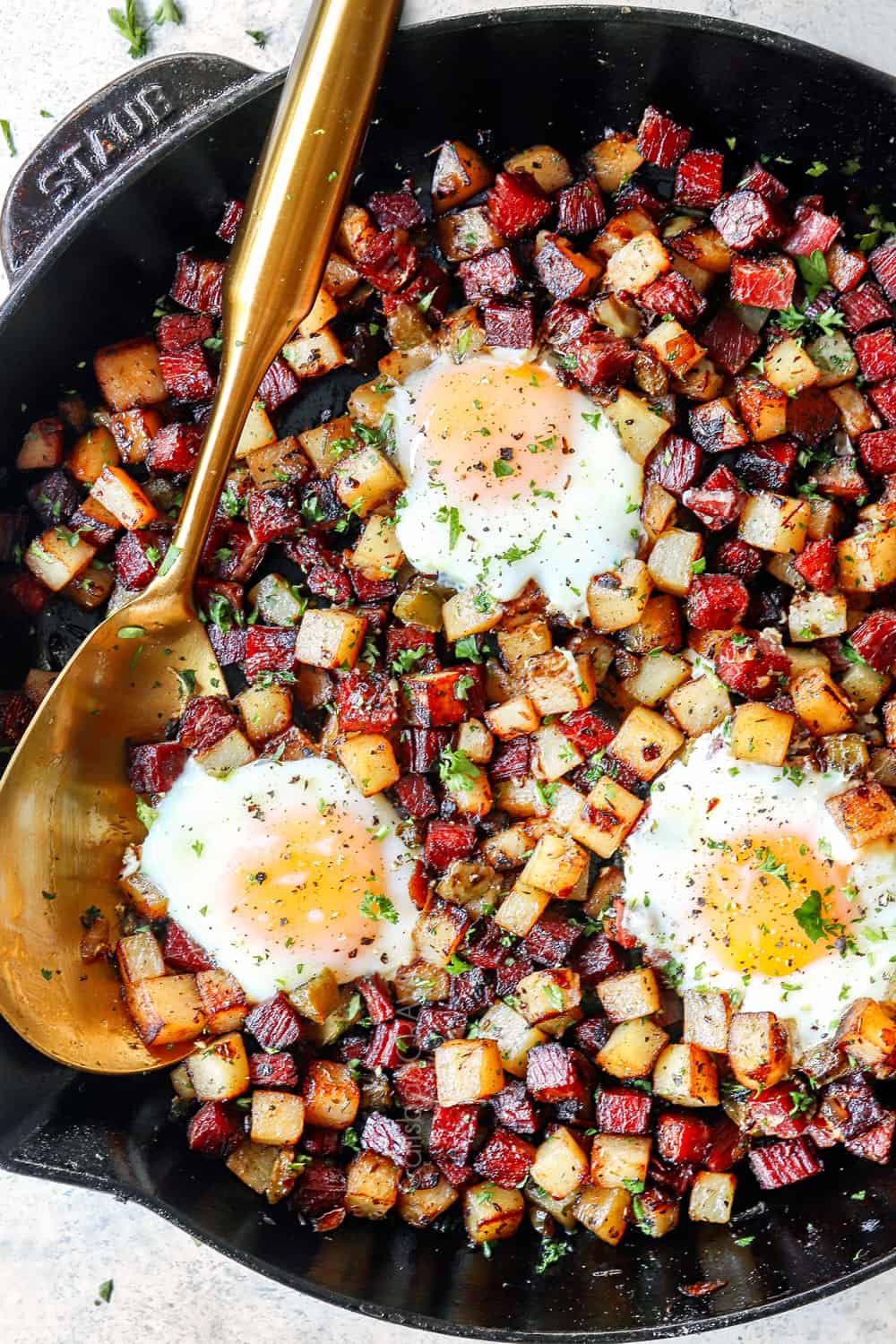 showing how to make corned beef hash with eggs by baking eggs in the skillet with the hash