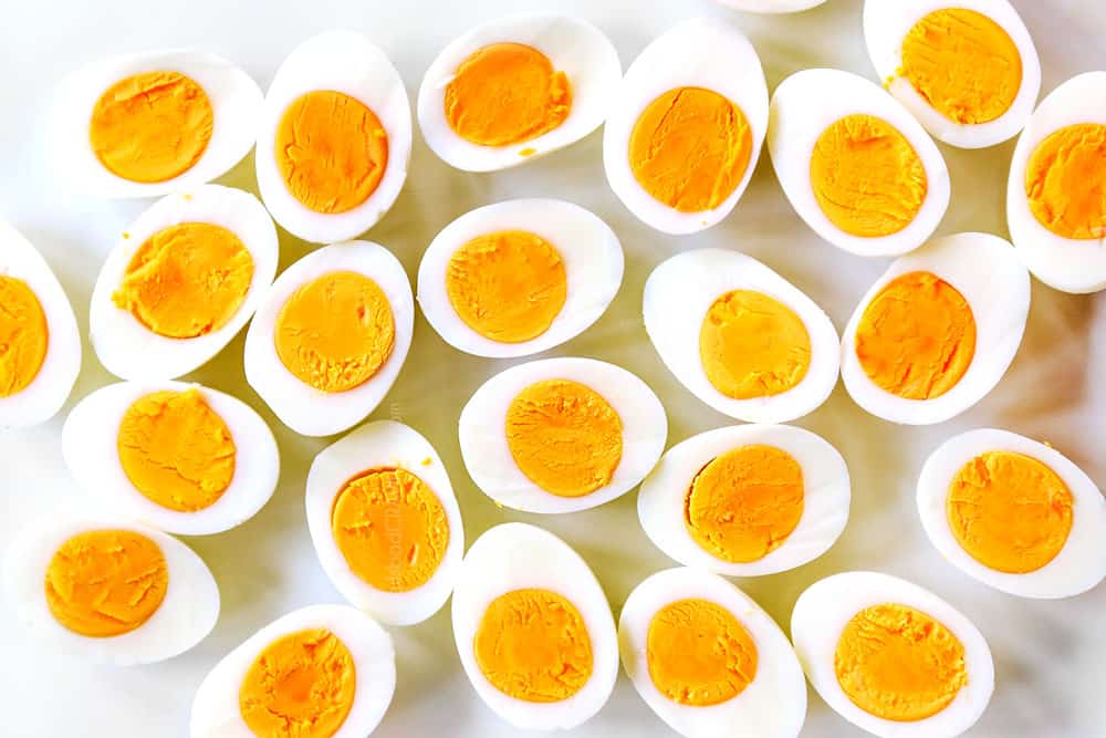 showing how to make deviled eggs by slicing hard boiled in eggs in half