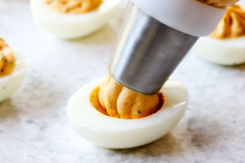 showing how to make deviled eggs by piping the filling into the egg white cavity