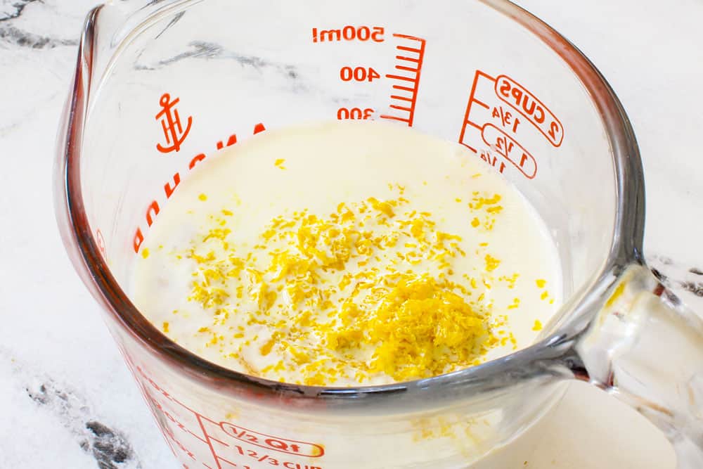 showing how to make lemon pound cake by adding lemon zest and lemon juice to buttermilk in a liquid measuring cup