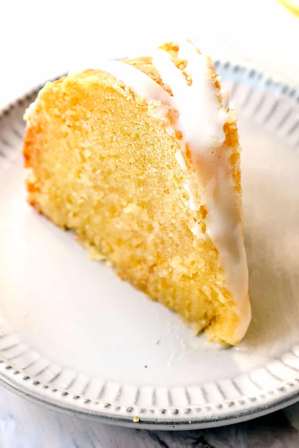 a slice of lemon pound cake on a plate with lemon glaze for cake