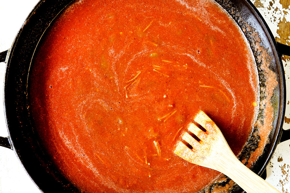 showing how to make fideo by adding fideo pasta to tomato sauce in skillet