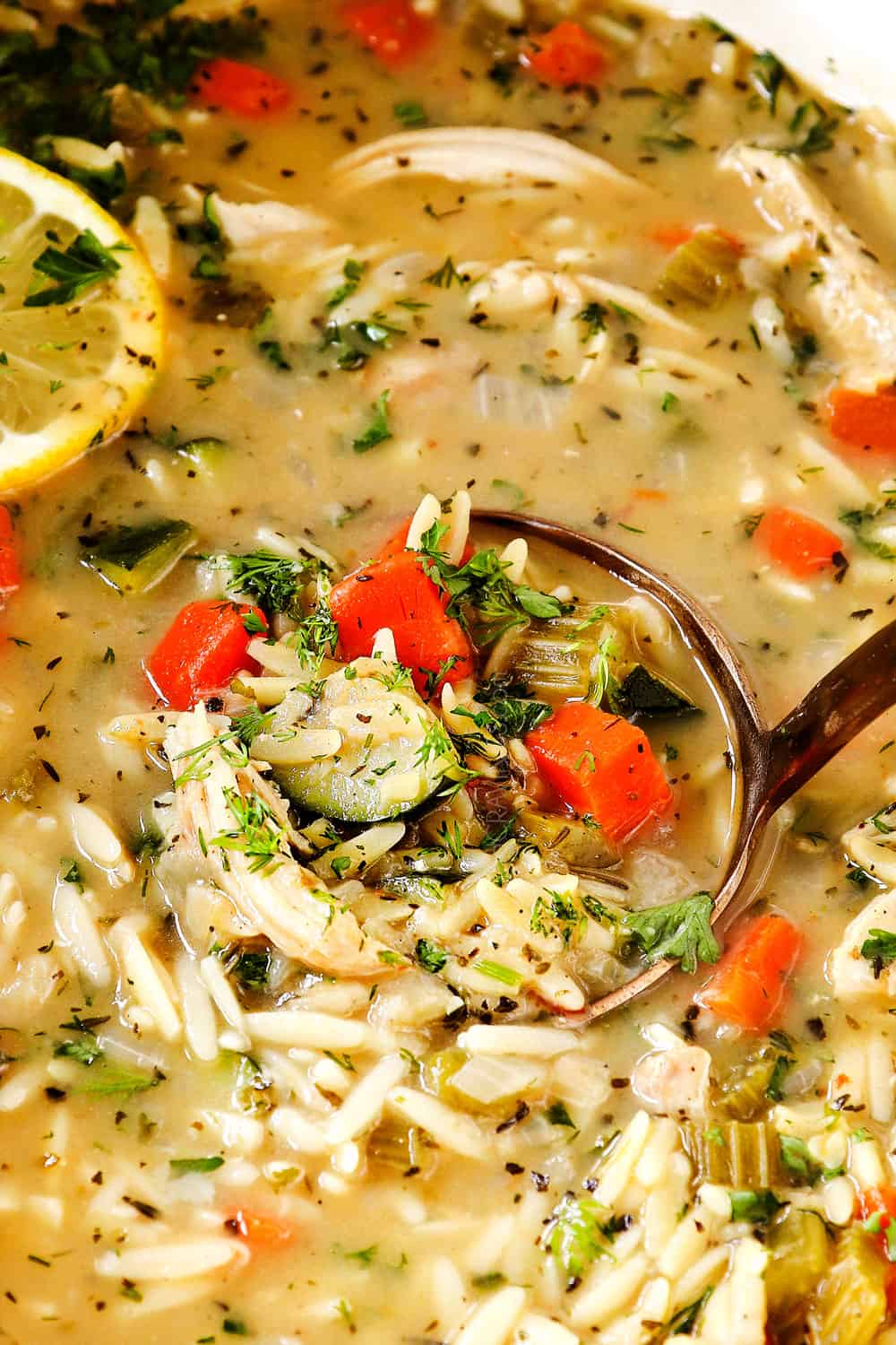 up close of a ladle scooping up lemon chicken orzo soup