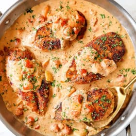 showing how to make Cajun chicken recipe by adding chicken to skillet with sauce