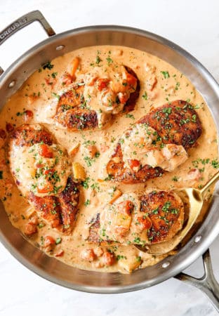 showing how to make Cajun chicken recipe by adding chicken to skillet with sauce
