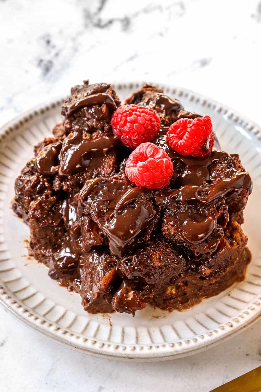 chocolate bread pudding recipe on a white plate drizzled with chocolate sauce