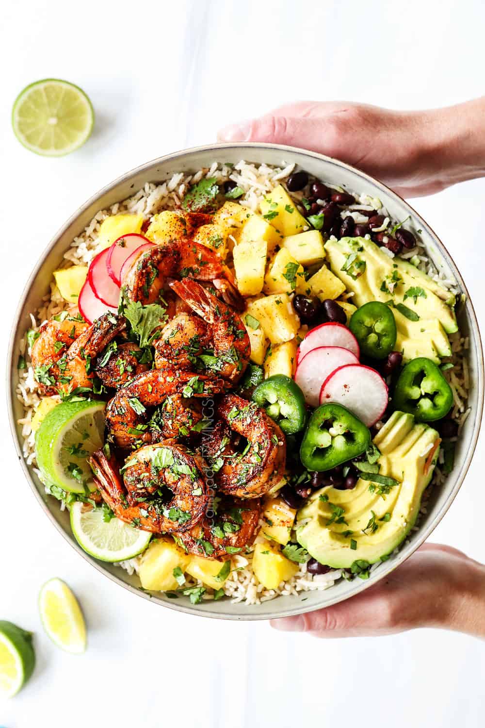 top view showing how to serve cilantro lime shrimp by adding to a bowl with rice, avocado and black beans
