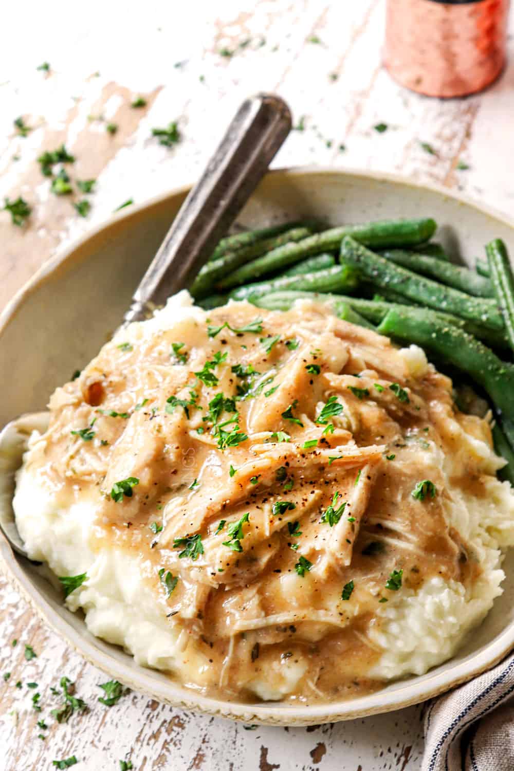 chicken and gravy on a bed of mashed potatoes garnished by parsley on a plate