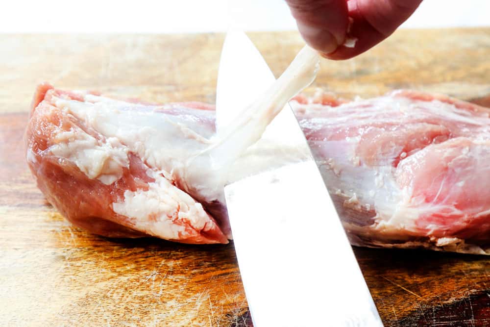 showing how to remove the silverskin from pork tenderloin by trimming it with a sharp knife