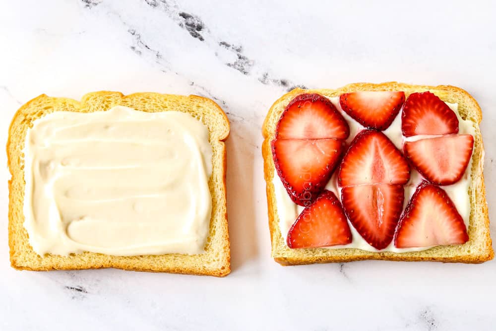 showing how to make stuffed French toast recipe by slathering one side of bread with cream cheese and topping another piece with cream cheese and strawberries