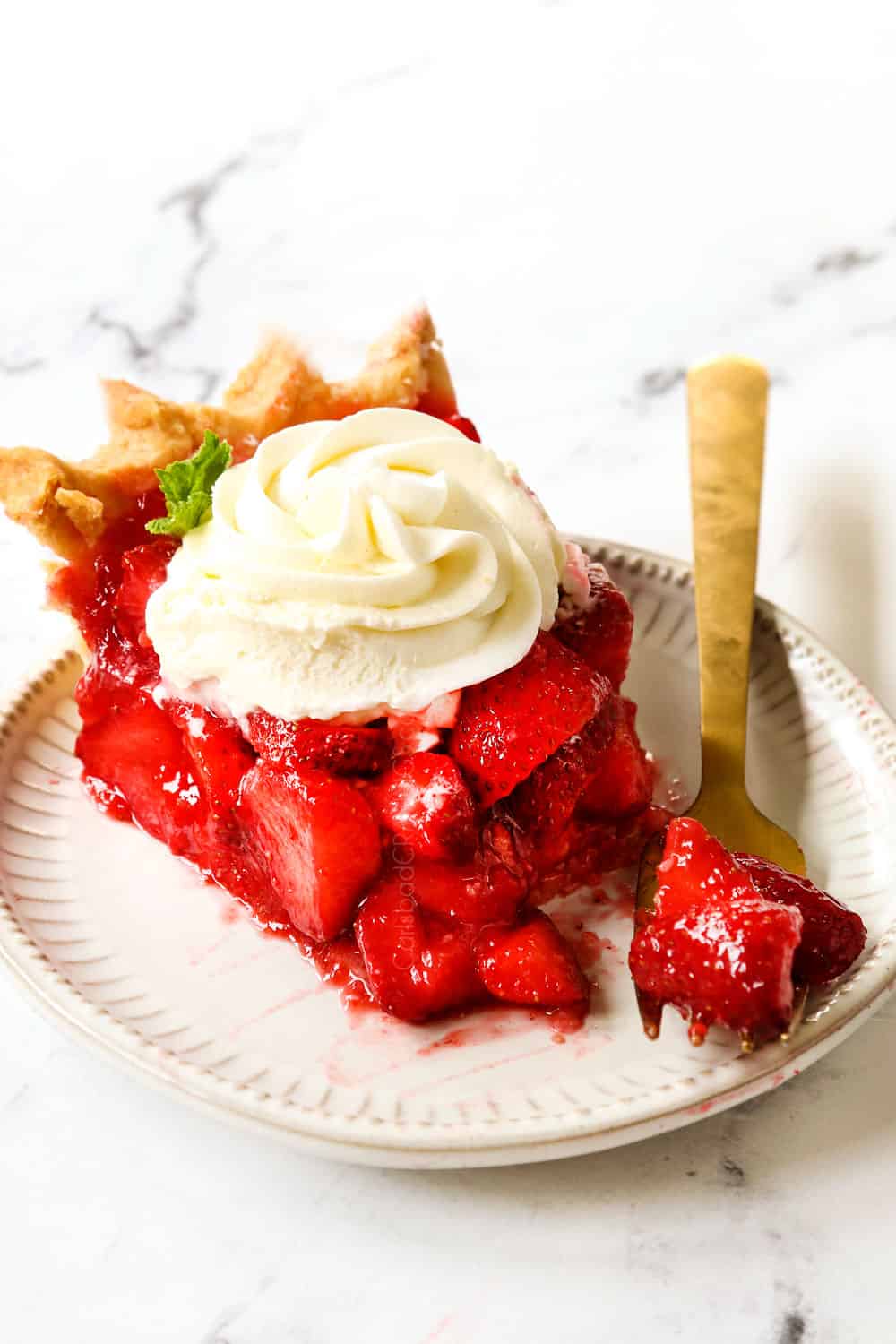 a slice of strawberry pie on a plate with whipped cream