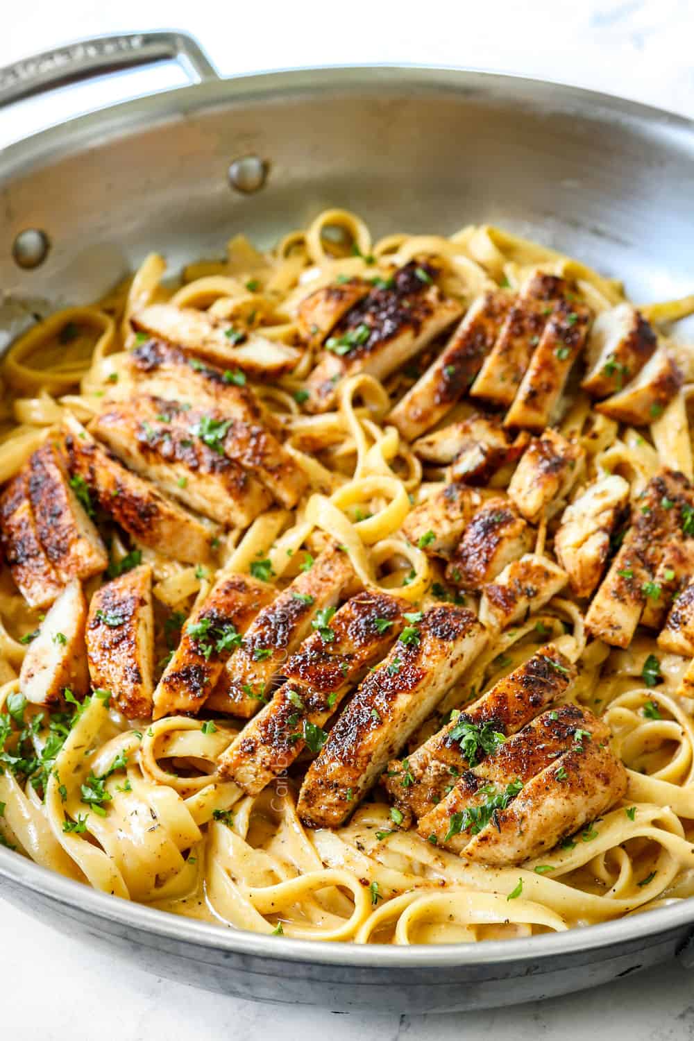 Blackened Chicken Alfredo in a skillet with sliced chicken breasts showing how juicy the chicken is