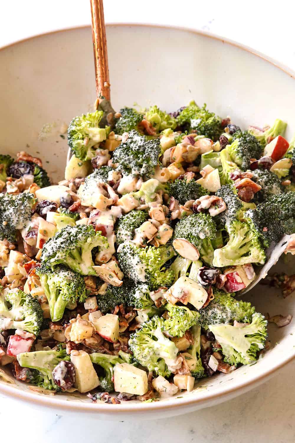  showing how to make best broccoli  salad recipe by tossing the broccoli bacon, cheese and apples with the dressing 