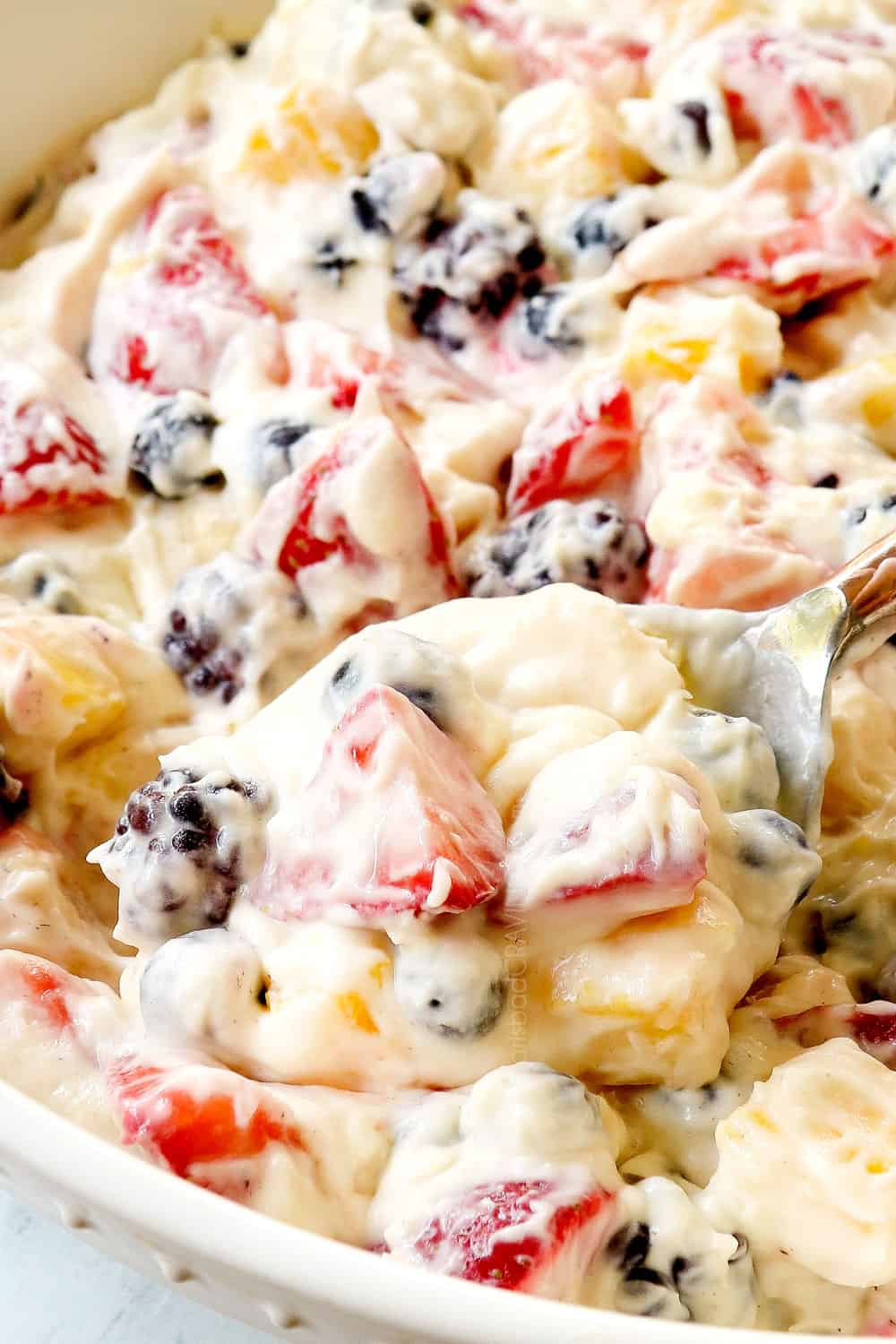 up close of a spoonful of cheesecake salad with strawberries and bananas showing how rich and creamy it is