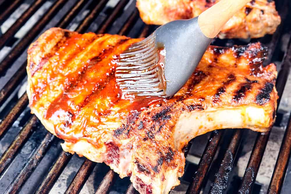 showing how to grill pork chops by brushing with barbecue sauce on the grill