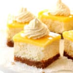 up close of lemon cheesecake bars with whipped cream on a cake pedestal