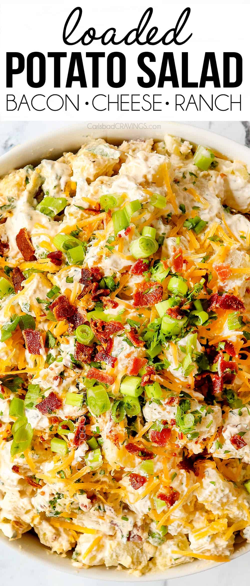 top view of loaded potato salad in a white bowl with bacon, cheese and chives