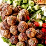 Greek Meatball recipe (Keftedes) with lamb meatballs on a platter with cucumbers and hummus