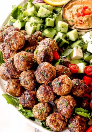 Greek Meatball recipe (Keftedes) with lamb meatballs on a platter with cucumbers and hummus