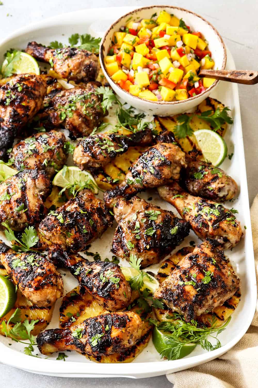 a platter of Jamaican Jerk Chicken garnished with cilantro and served with mango salsa