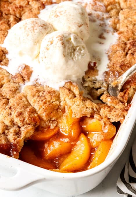 up close of scooping easy peach cobbler with fresh peaches
