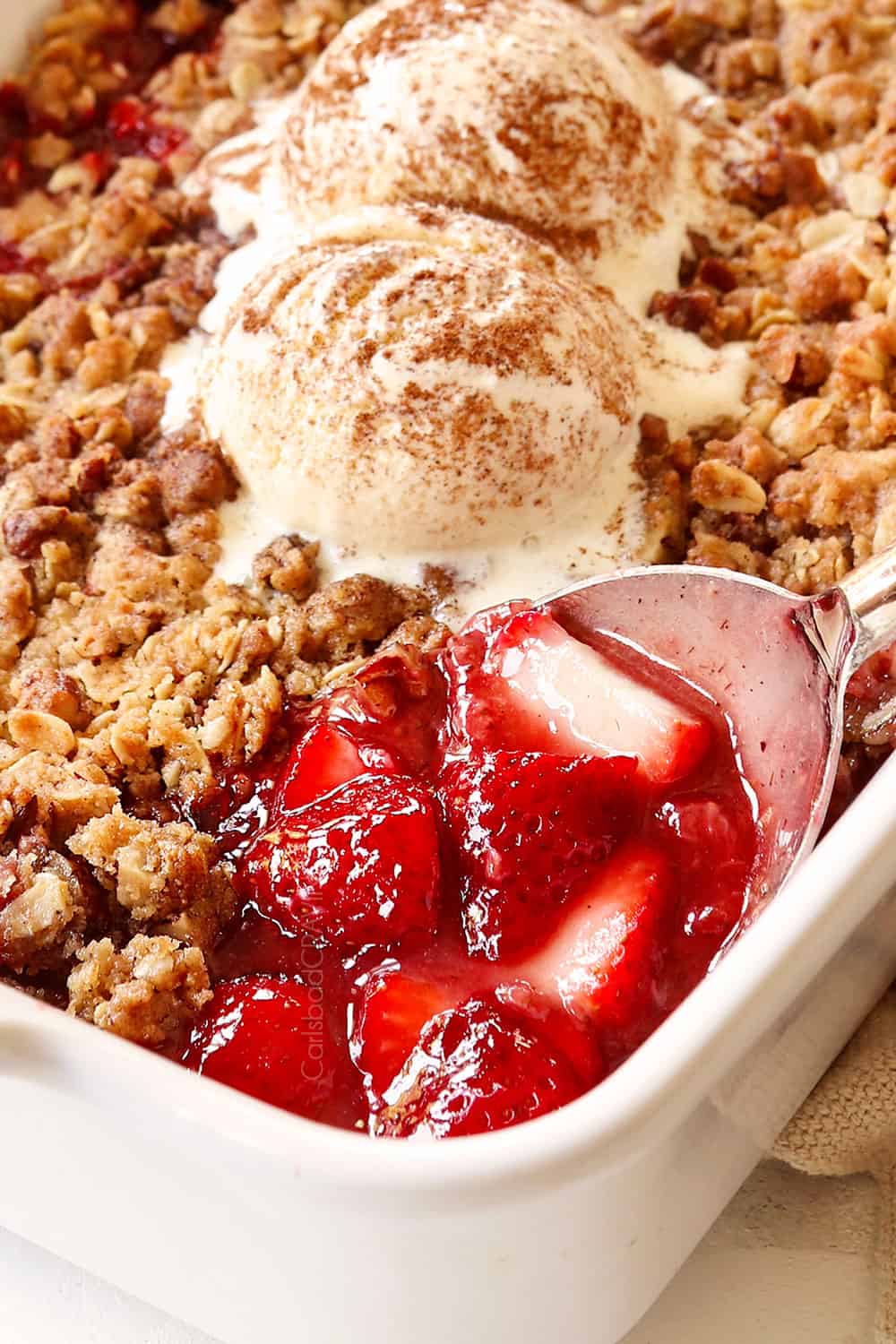 up close of a spoonful of strawberry crumble (crisp) showing the juicy strawberry filling