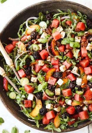 top view of a large serving bowl of watermelon salad with feta, basil, mint, cucumbers and arugula