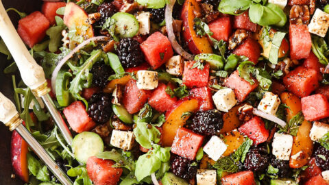 top view of a large serving bowl of watermelon salad with feta, basil, mint, cucumbers and arugula