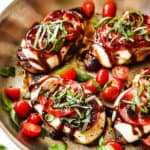 showing how to make chicken caprese by adding basil to chicken in the skillet